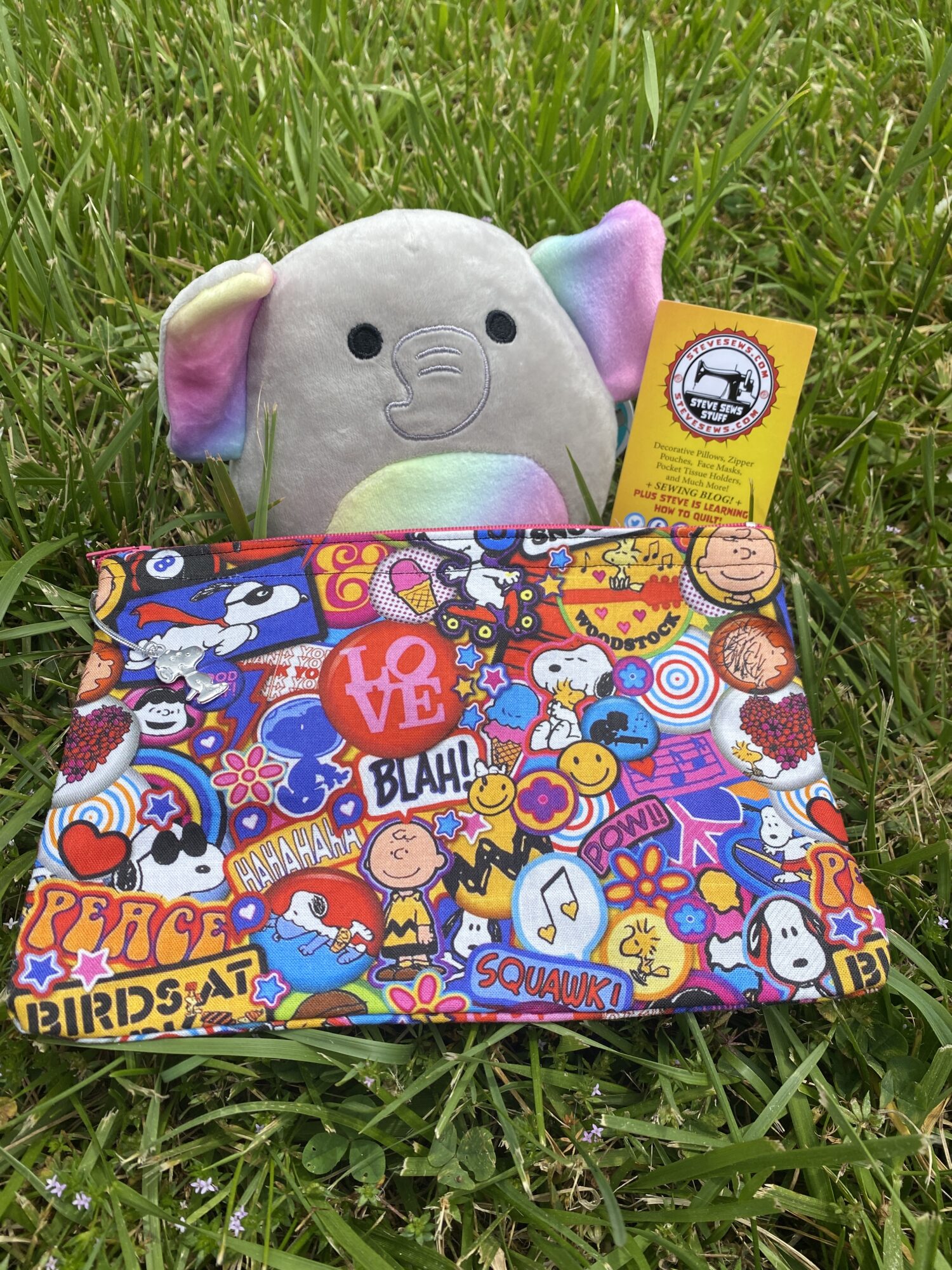 Meet Mila our newest loveee (Squishmallow). 
She is showing off Retro Snoopy Zipper Pouch – a very colorful retro-looking pocket tissue holder featuring some of the Peanuts Gang along with Snoopy. With a Snoopy Zipper Pull!