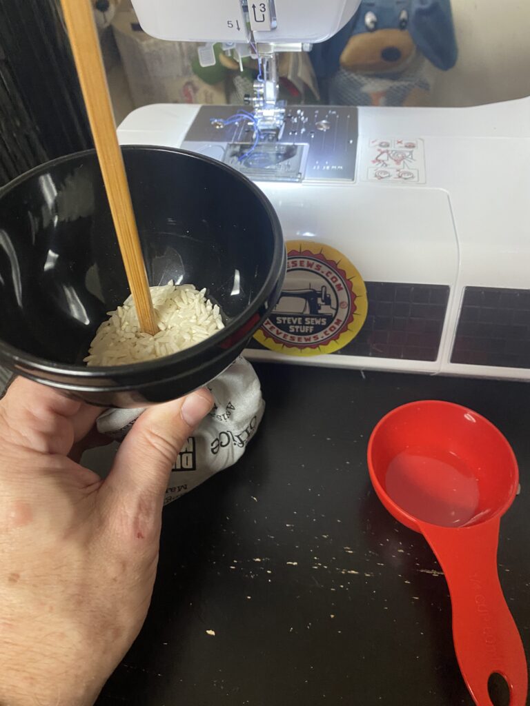 Use a funnel to do this. That chop stick can also help push the rice down the funnel. 