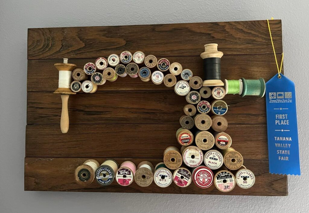 Sewing Machine Art this is a piece of art featuring antique wooden thread spools and shaped like an antique sewing machine. 