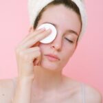 Woman removing eye makeup with cotton pad