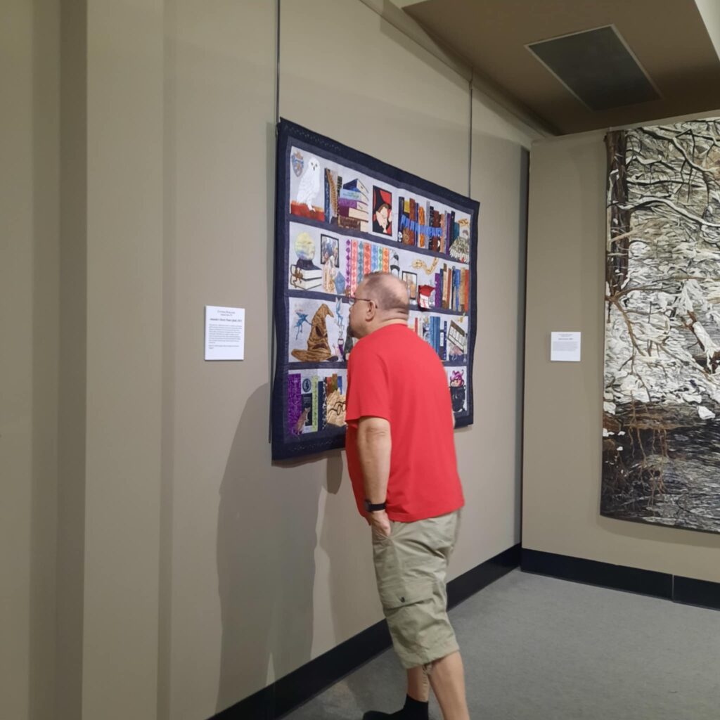 Steve is looking up close at the detail of Cynthia England’s Amanda’a Harry Potter Quilt.